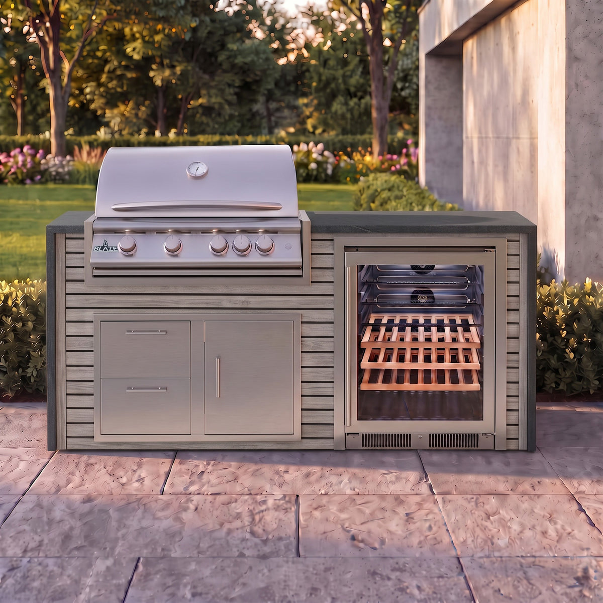 Drifted Cypress outdoor kitchen with Charred Onyx granite countertop on a stone paver patio beside a backyard garden