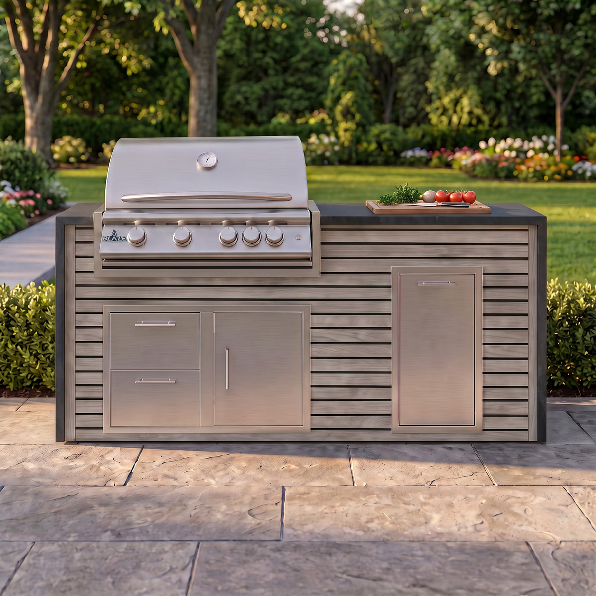Drifted Cypress grill island with Charred Onyx granite top and a cutting board of fresh tomatoes on a paver patio facing the lawn