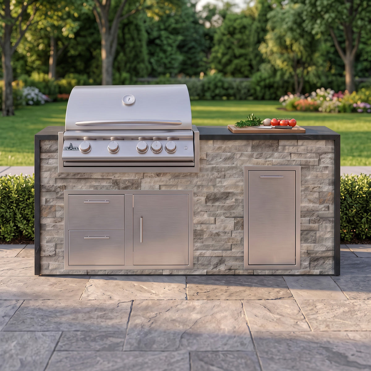 Tuscan Hearth grill island with Charred Onyx granite top and a cutting board of fresh tomatoes on a paver patio facing the lawn
