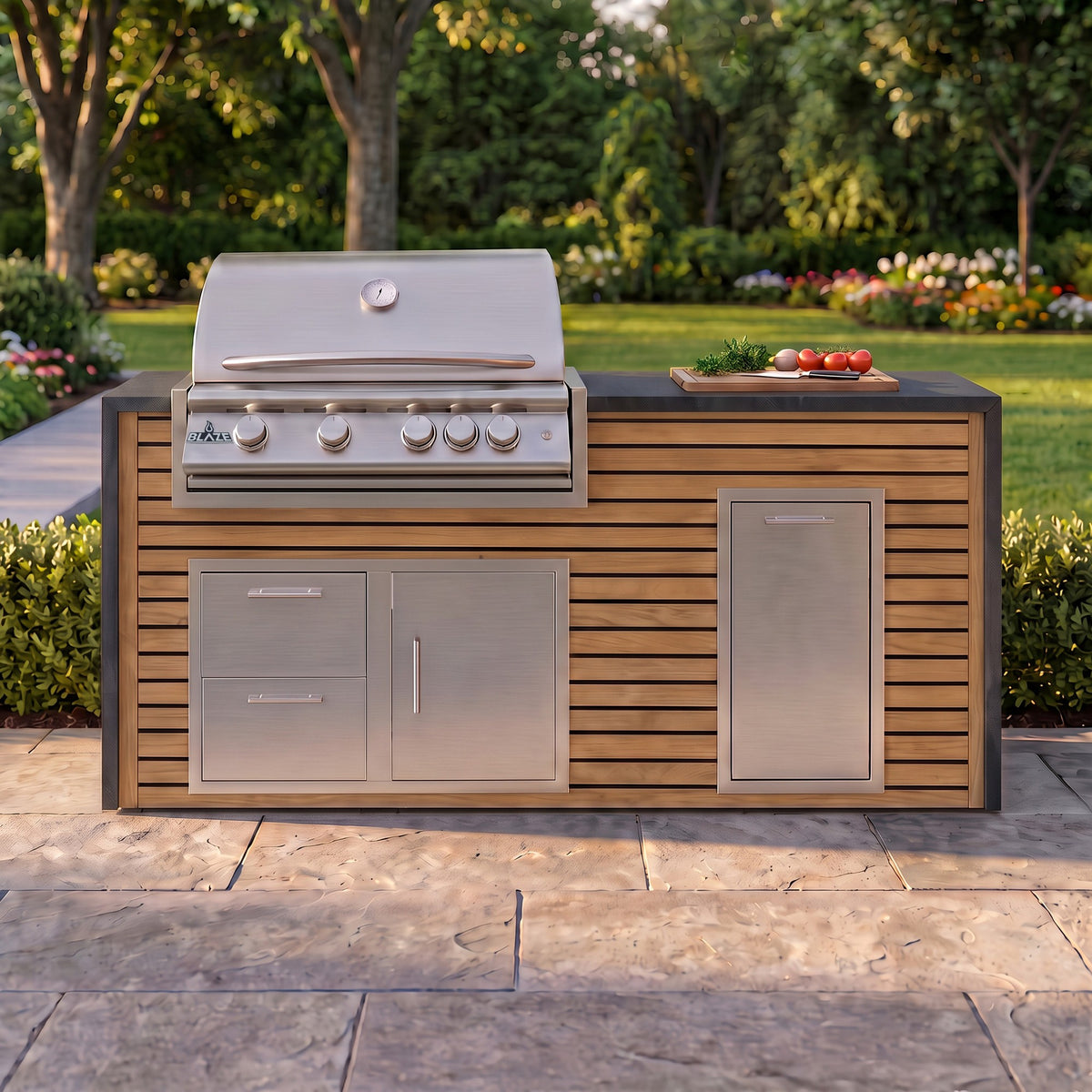 Warmed Acacia grill island with Charred Onyx granite top and a cutting board of fresh tomatoes on a paver patio facing the lawn