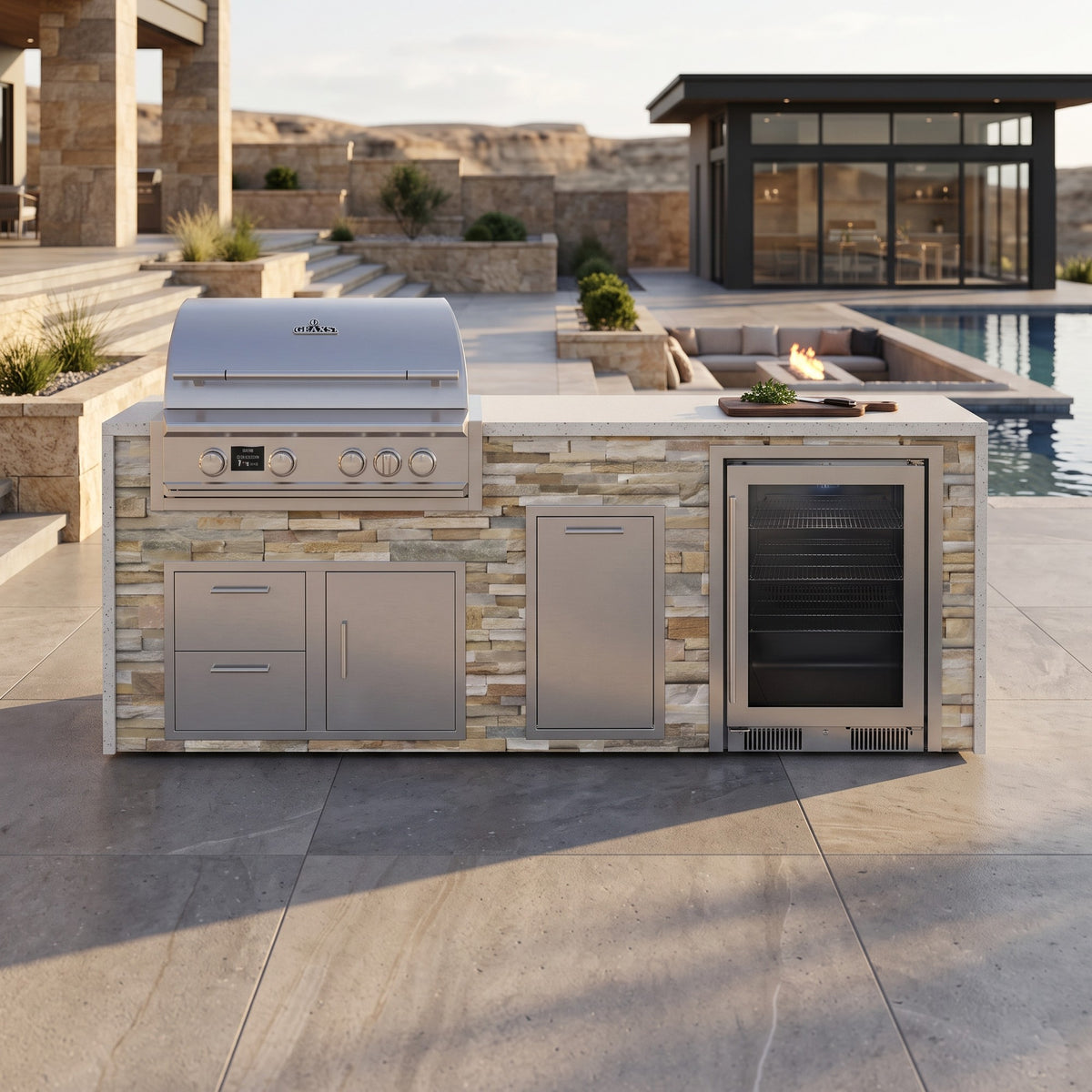 Sunkissed Dune outdoor kitchen with beverage cooler and Frosted Ember granite top on a stone patio near a sunken fire pit lounge, pool and glass pool house