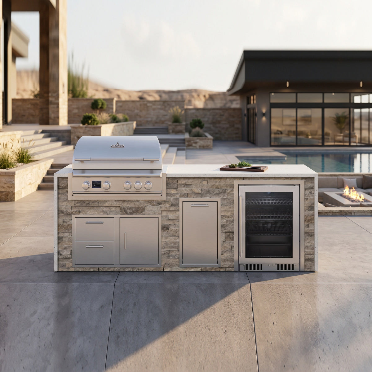 Tuscan Hearth outdoor kitchen with beverage cooler and Frosted Ember granite top on a concrete patio by a sunken fire pit and pool with desert hills beyond