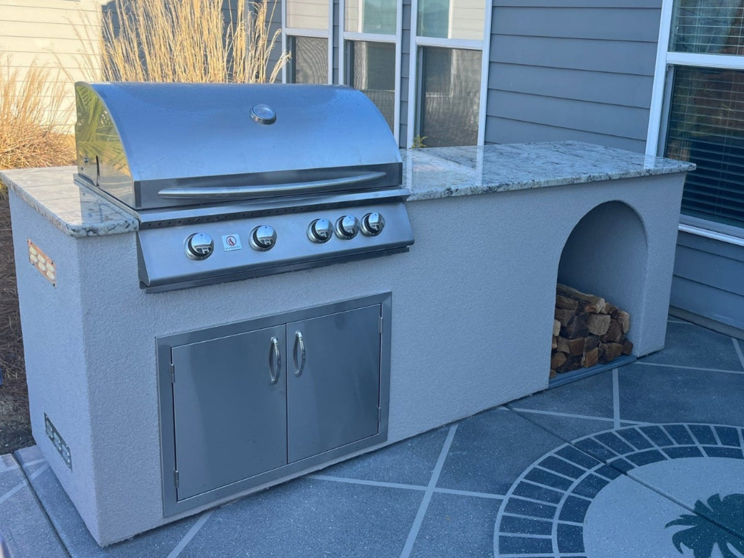 Stucco outdoor kitchen with built-in gas grill, granite countertop, and stainless storage doors