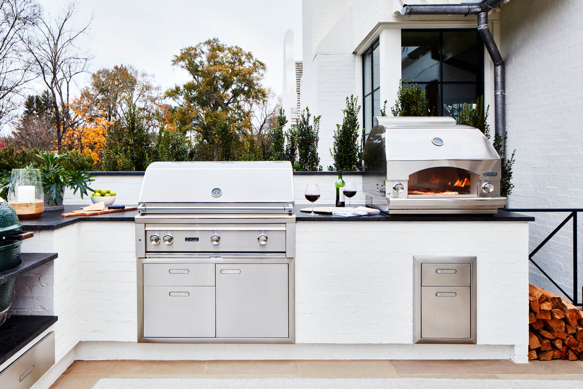Lynx grill and pizza oven in a white outdoor kitchen