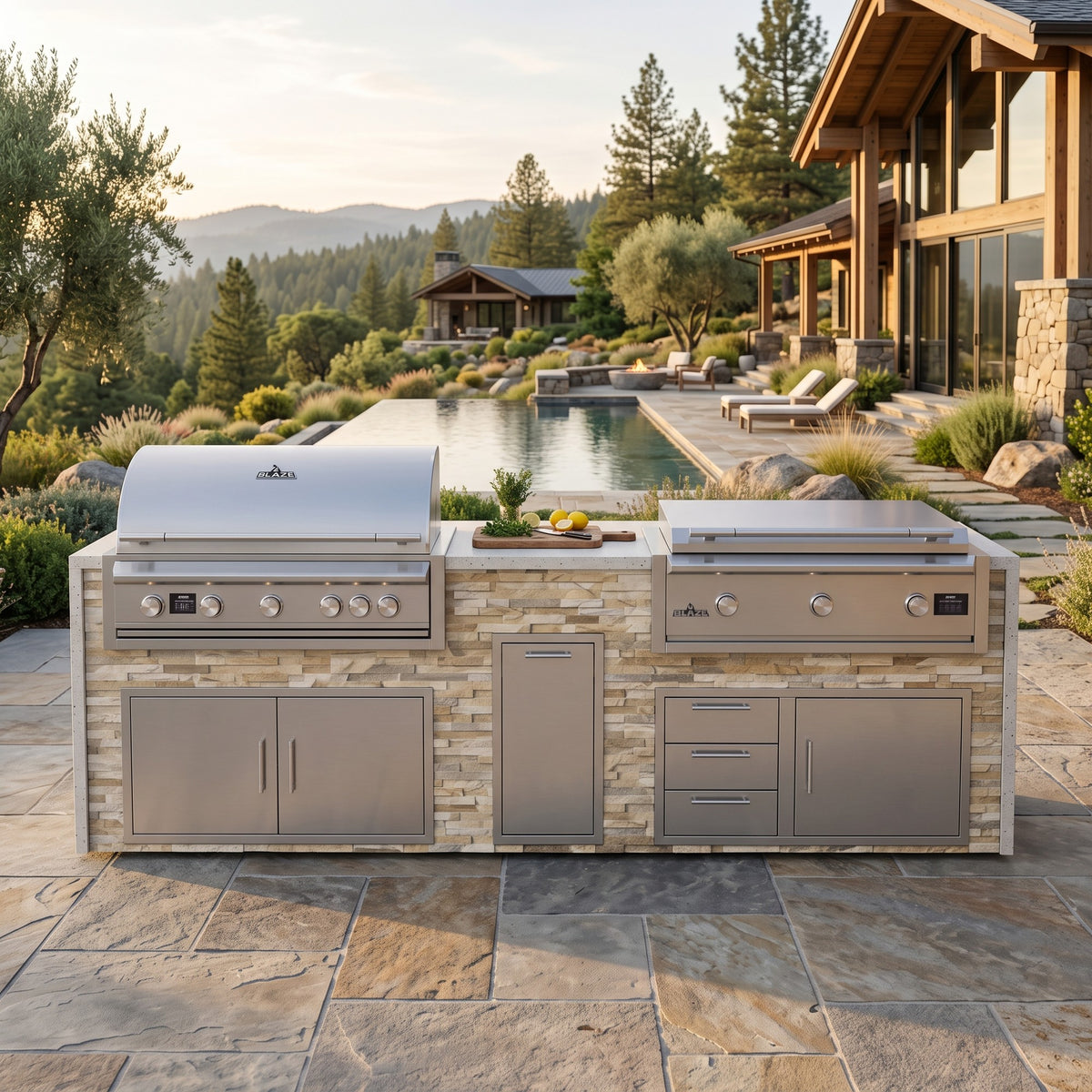 Sunkissed Dune grill and griddle island with Frosted Ember granite top on a flagstone patio beside an infinity pool and timber lodge with mountains beyond