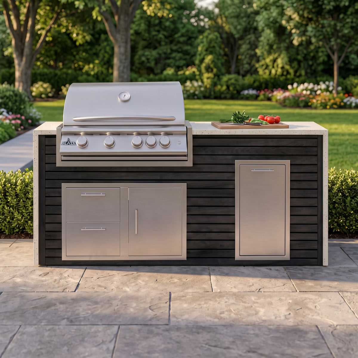 Cindered Ash grill island with Frosted Ember granite top and a cutting board of fresh tomatoes on a paver patio facing the lawn