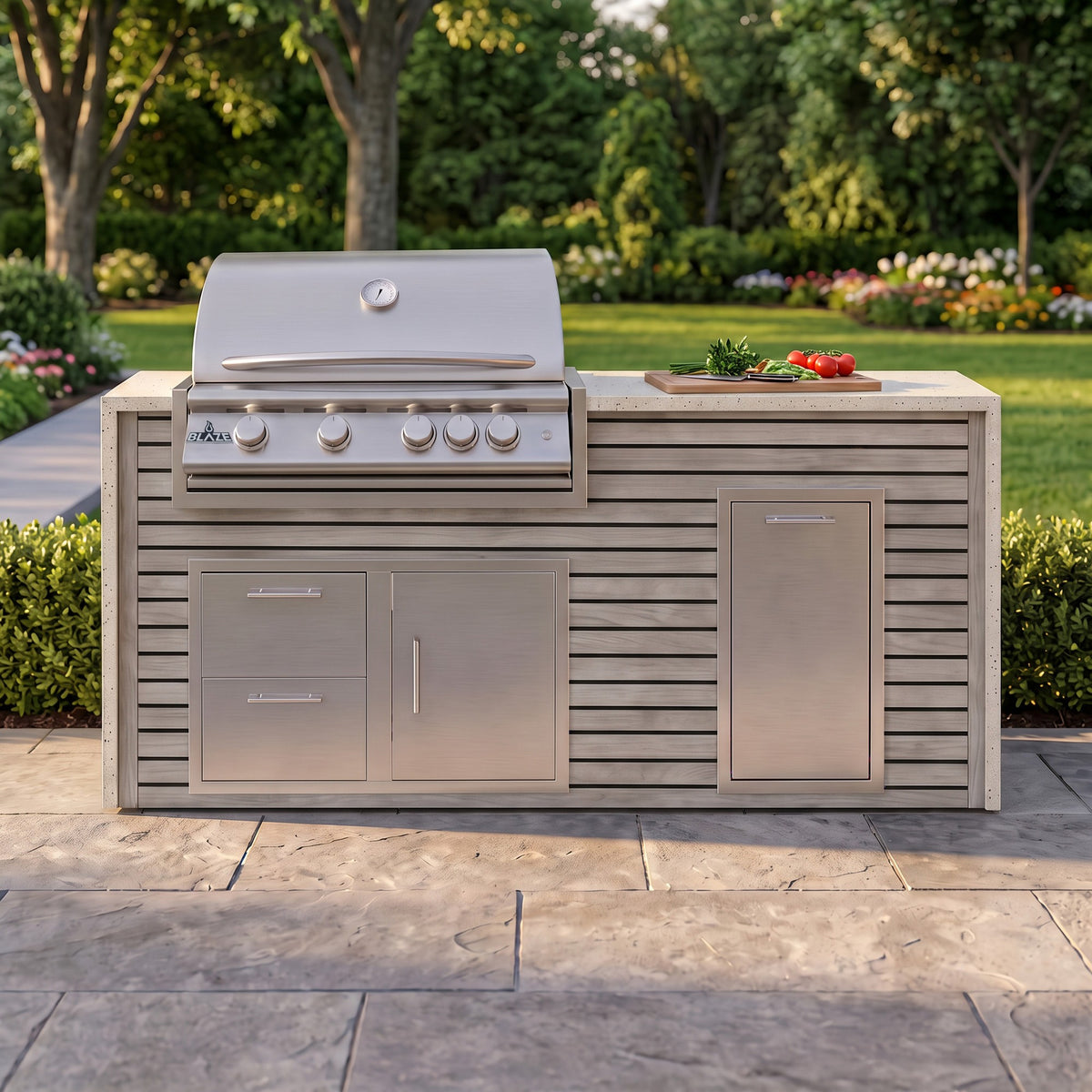 Drifted Cypress grill island with Frosted Ember granite top and a cutting board of fresh tomatoes on a paver patio facing the lawn