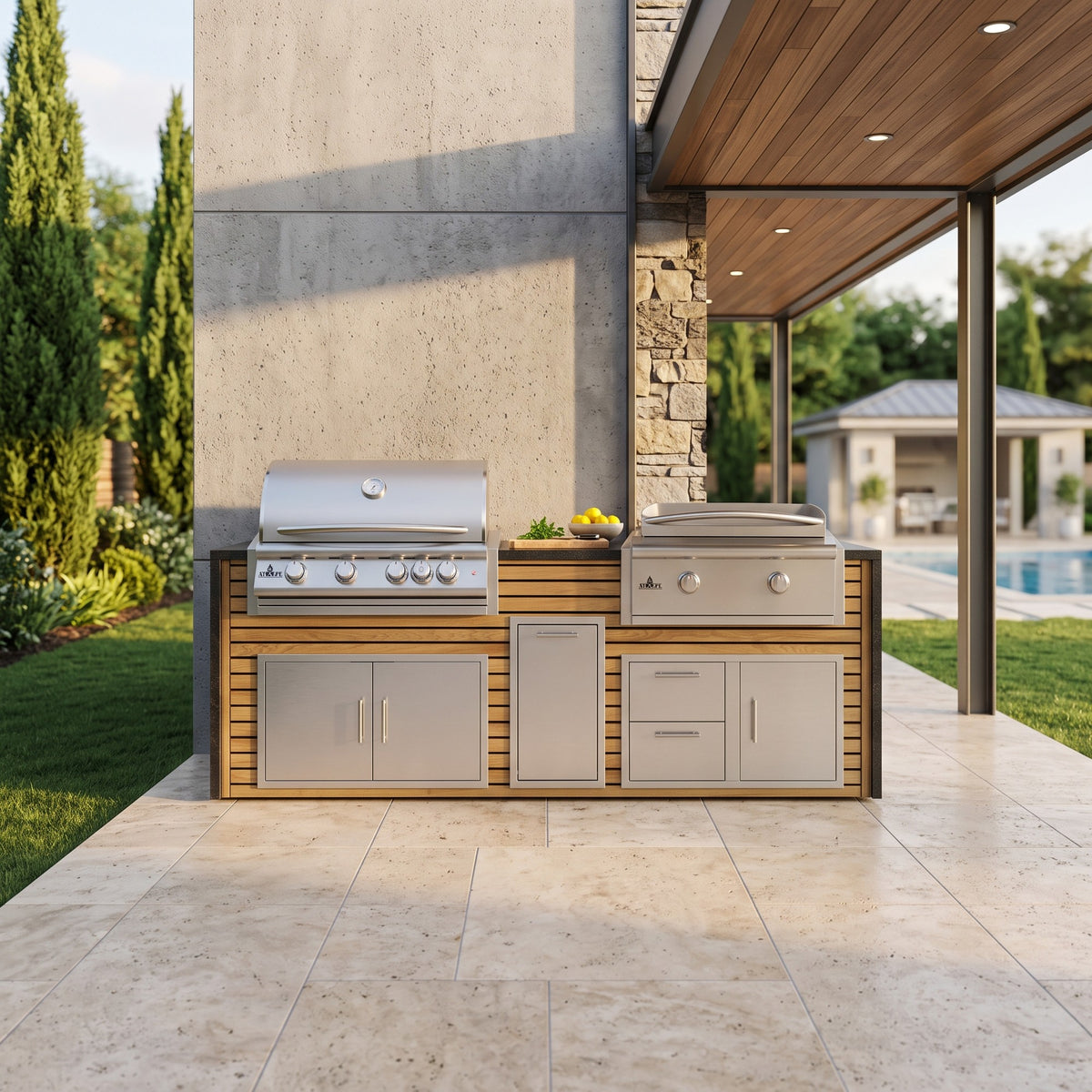 Warmed Acacia grill and griddle island with Charred Onyx granite top on a covered travertine patio beside the house with the pool behind