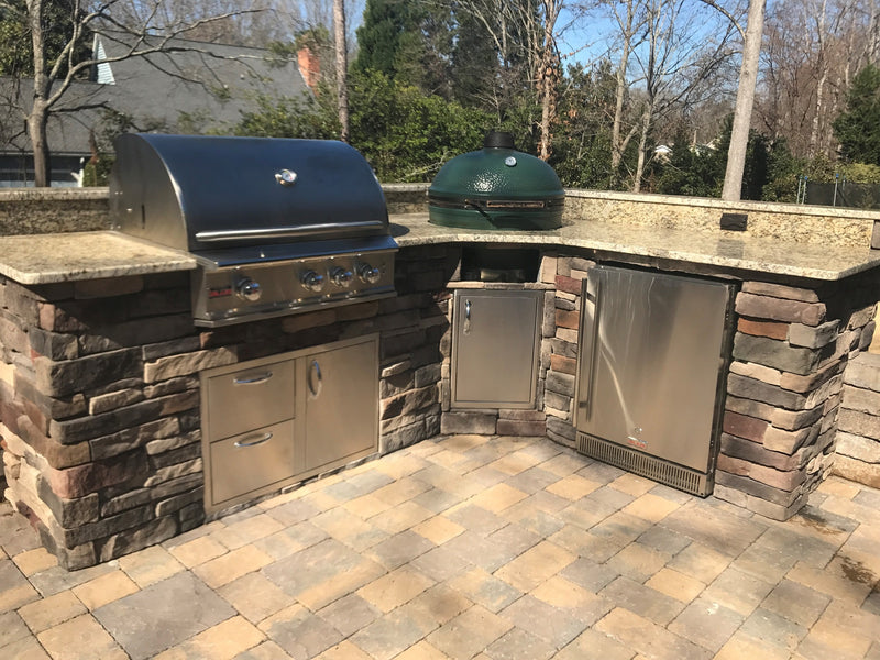 L-shaped outdoor kitchen with stone veneer, built-in grill, refrigerator, and Big Green Egg smoker