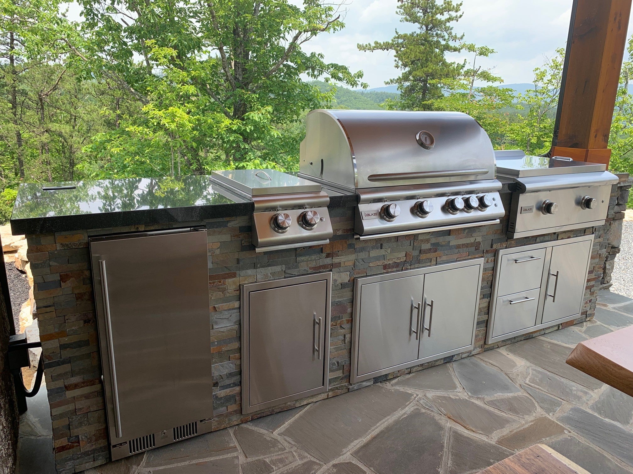 Custom outdoor kitchen with built-in grill, side burner, and stone veneer facing