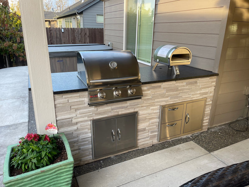 Compact outdoor kitchen with built-in grill, pizza oven, and stone veneer finish